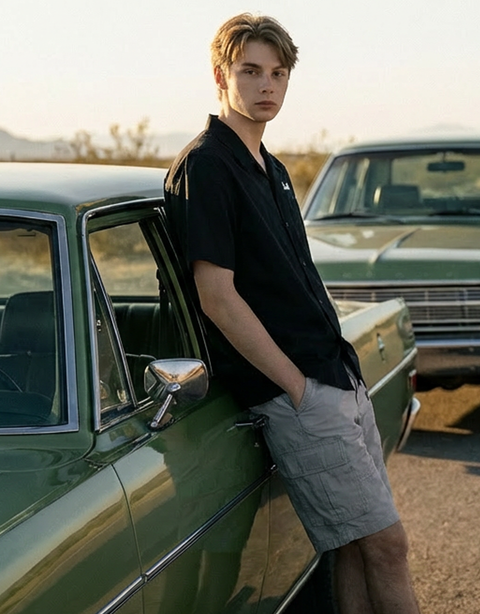 The male model wearing Smith's 1906 clothing leans casually against the car with his hands in his pockets.